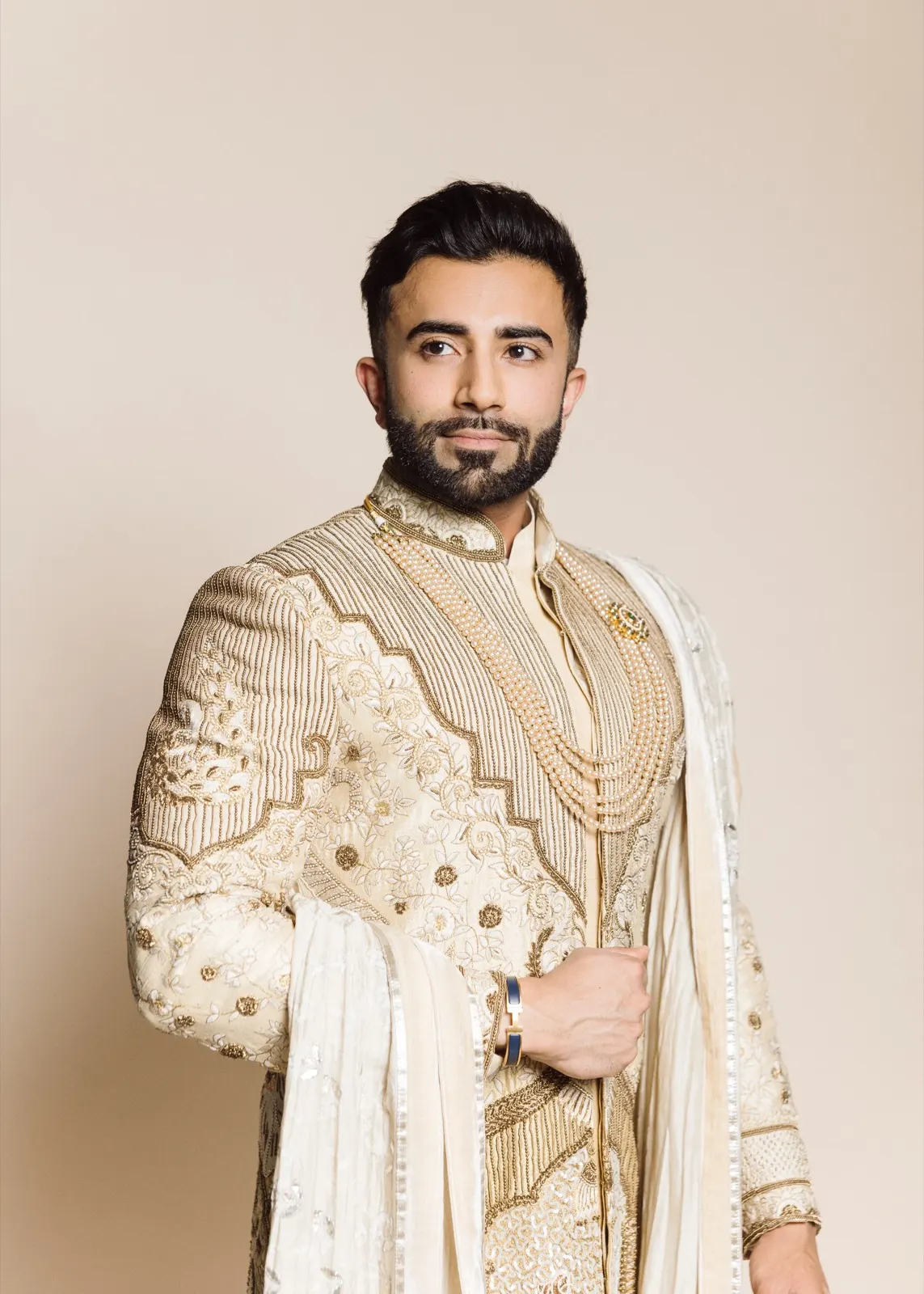 Hemel poses in a richly embroidered cream-and-gold sherwani with layered pearls and a draped stole.
