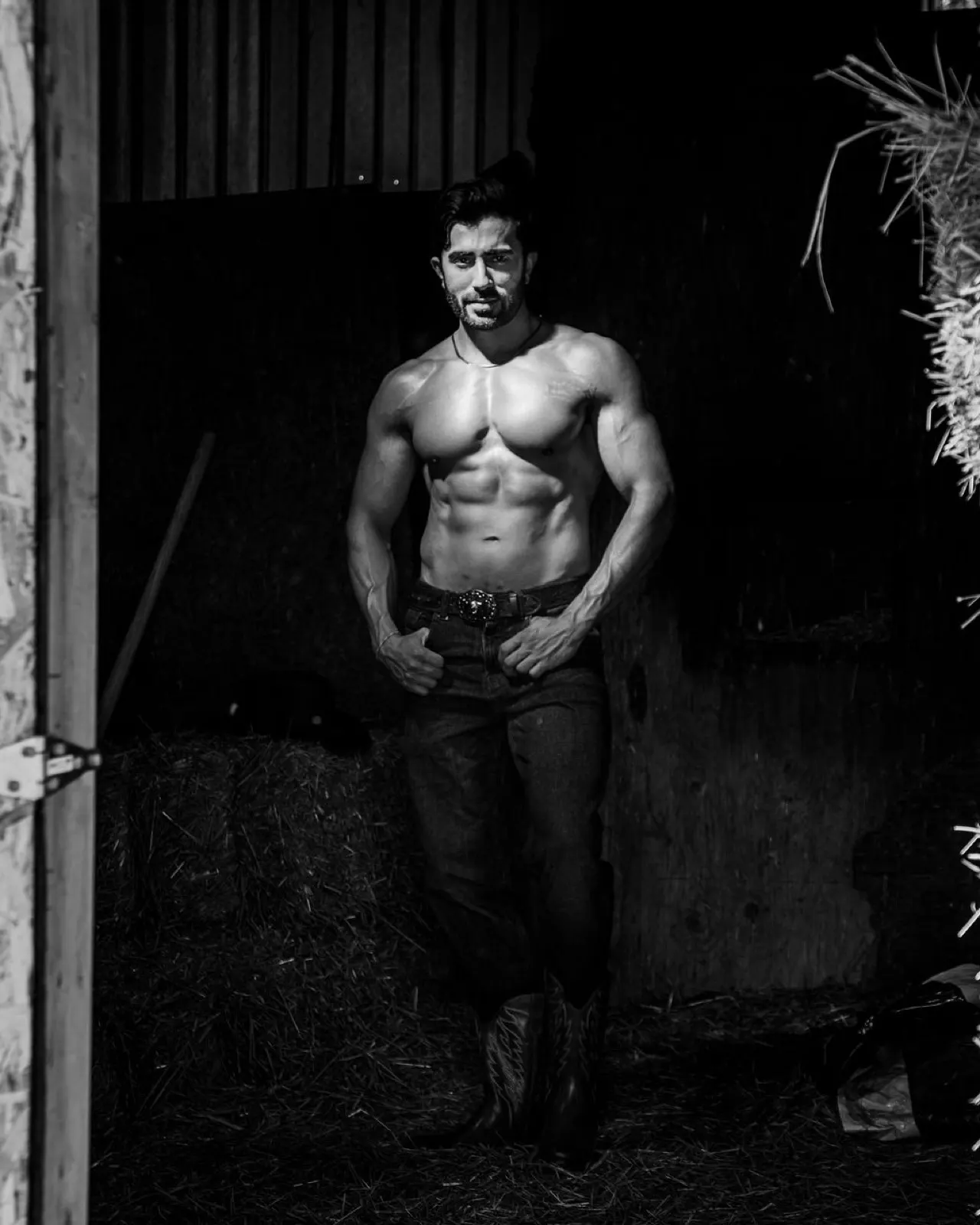 Hemel faces the camera in a black and white stable portrait with dramatic contrast and western styling.
