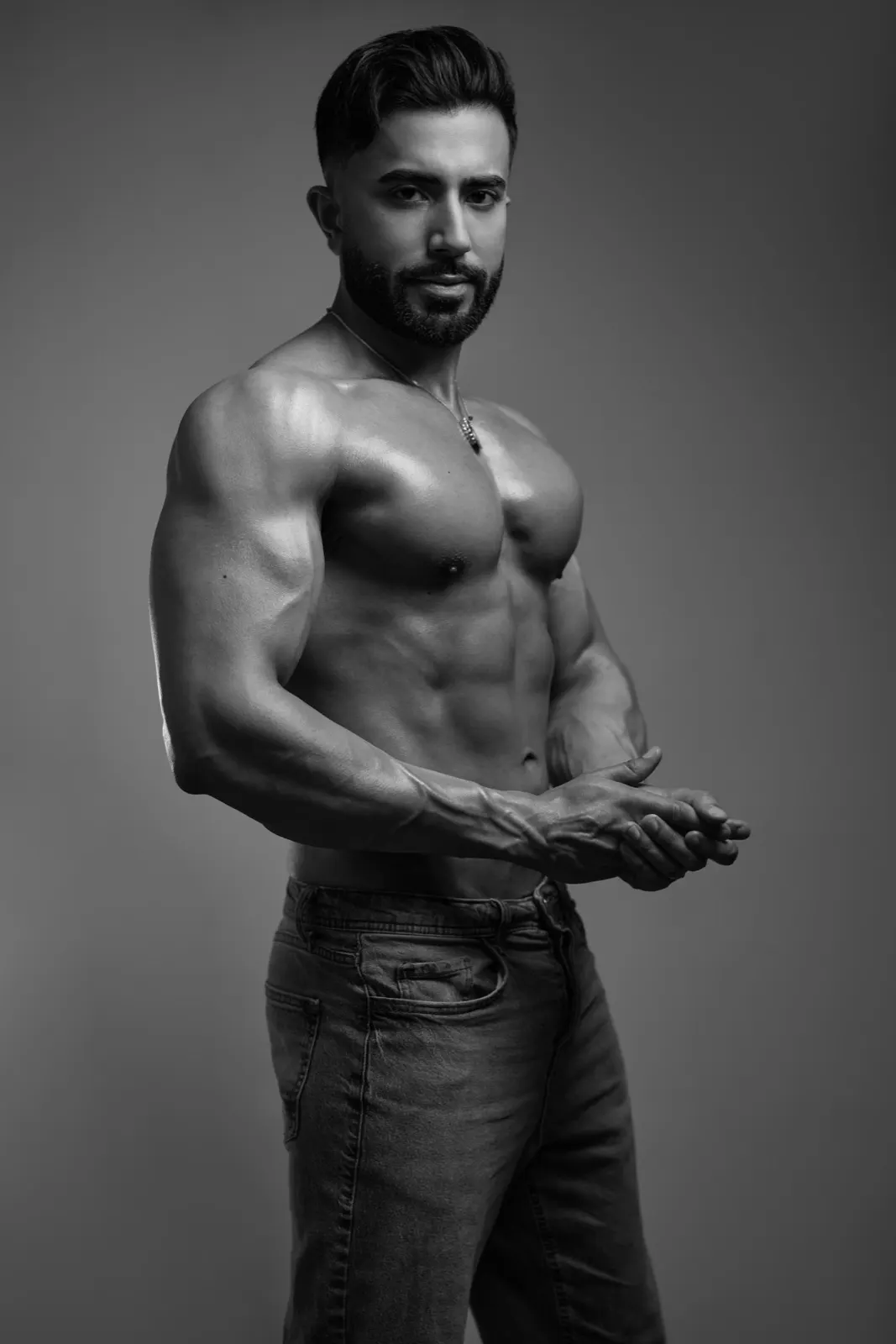 Hemel poses shirtless in a black-and-white studio portrait, highlighting his athletic physique and confident presence.