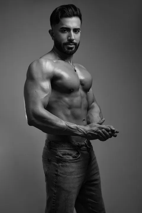 Hemel poses shirtless in a black-and-white studio portrait, highlighting his athletic physique and confident presence.