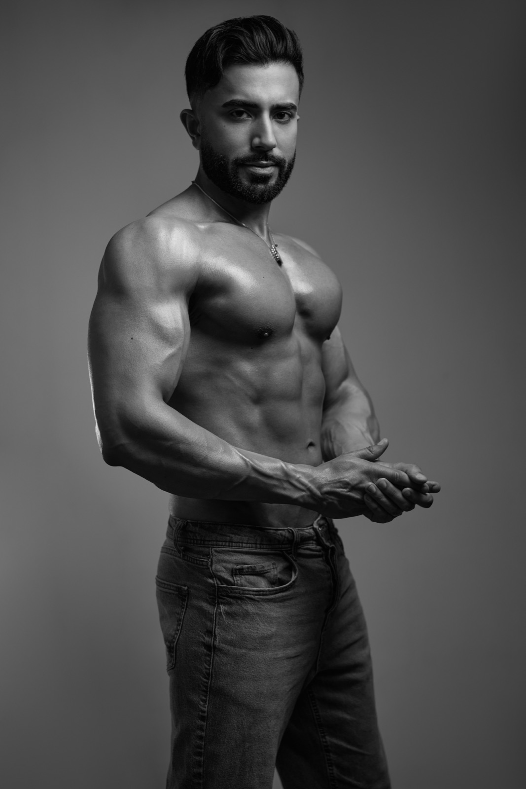 Hemel poses shirtless in a black-and-white studio portrait, highlighting his athletic physique and confident presence.