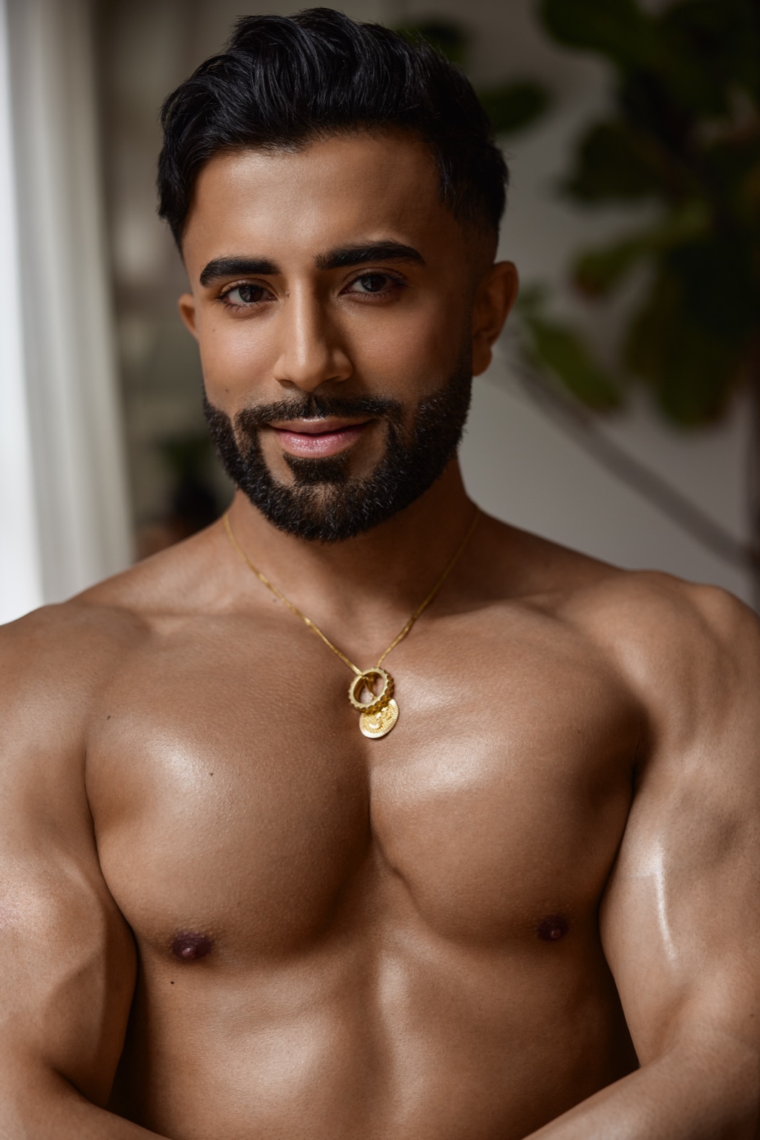 Hemel faces the camera in a close shirtless portrait with warm natural light and a gold necklace.